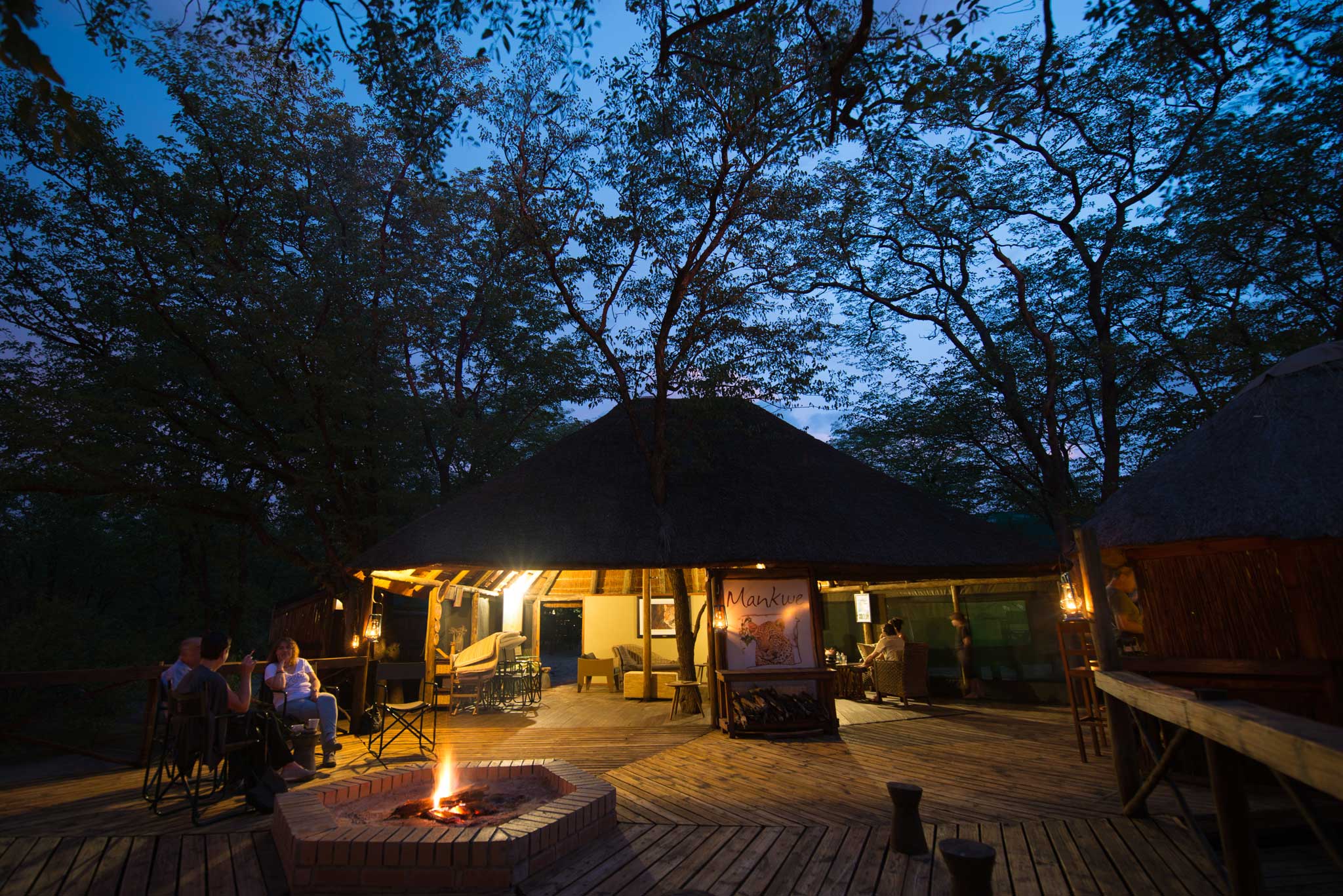 Open-air boma fire and thatched lounge behind