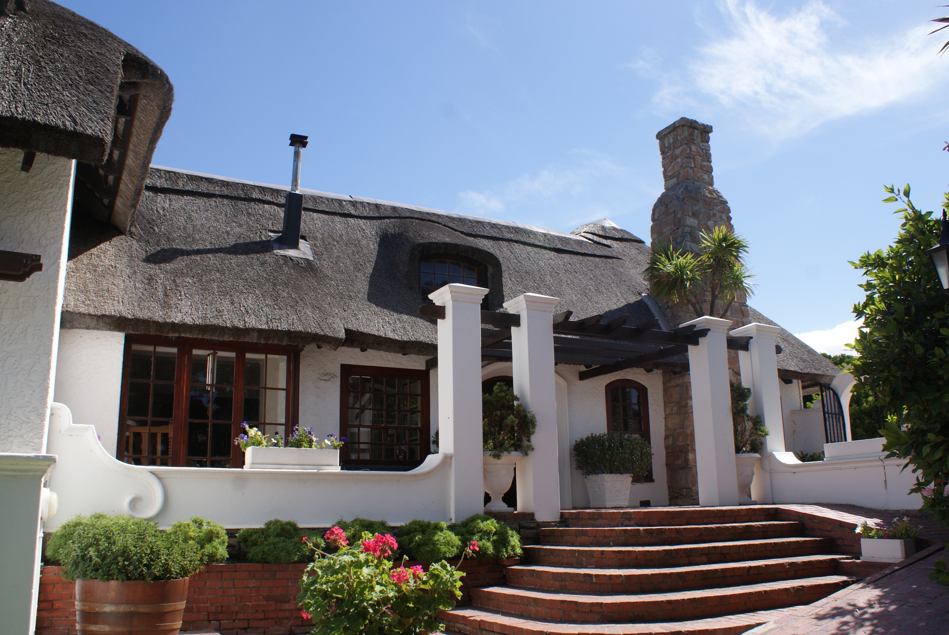 The characteristic front entrance of the main building of Whale Rock Luxury Lodge with the typical Hermanus style rock chimney.